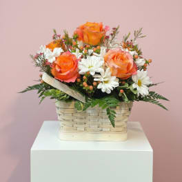 Basket arrangement of orange roses and white daisies