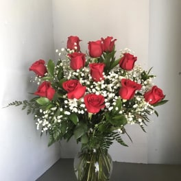 Red roses arranged in a clear glass vase with white baby's breath