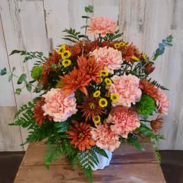 Pink and orange floral arrangement in a white vase