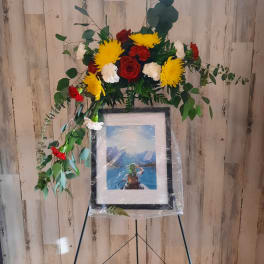 Floral standing spray with red, yellow, and white flowers on an easel