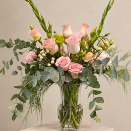 Pink roses and pale blooms arranged in a clear glass vase