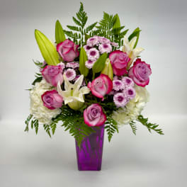 Pink roses and white lilies arranged in a purple vase