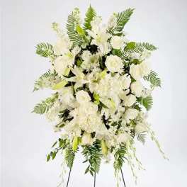 Large white funeral spray with lilies and roses on a standing easel