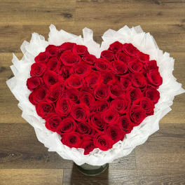 Heart-shaped bouquet of red roses wrapped in white paper