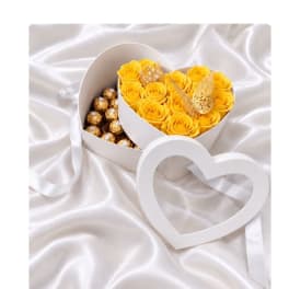 Yellow roses in a heart-shaped box with chocolates and a ribbon