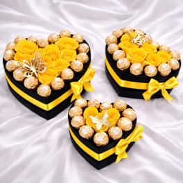 Heart-shaped gift boxes with yellow roses and chocolates on satin fabric