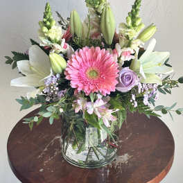 Pink gerbera bouquet with white lilies and lavender roses in a glass vase