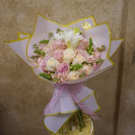Bouquet of pink and white roses wrapped in pale paper with a pink ribbon