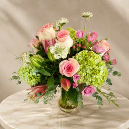 Pink and white roses with green hydrangeas in a clear glass vase