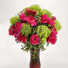 Pink roses and carnations with green pom-pom blooms in a red vase