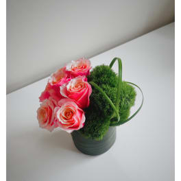 Pink roses arranged with green moss balls in a dark pot
