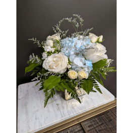 White and pale blue floral arrangement in a square vase