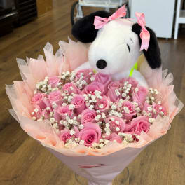 Pink rose bouquet with baby’s breath and a Snoopy plush topper