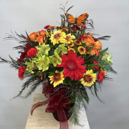 Colorful mixed bouquet in a dark vase with a butterfly pick