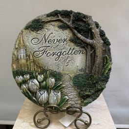 Round memorial plaque with the words "Never Forgotten" and tulips