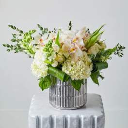 White and pale peach floral arrangement in a silver vase