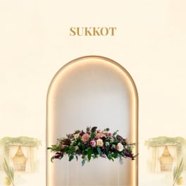 Low floral centerpiece with pink and peach blooms under the word Sukkot