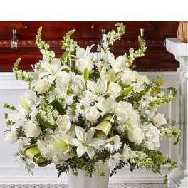 White floral arrangement in a white vase with lilies and daisies