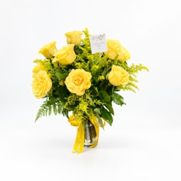 Yellow roses arranged in a glass vase with a yellow ribbon