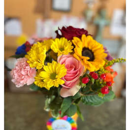 Mixed bouquet with sunflowers, roses, and pink carnations in a glass vase
