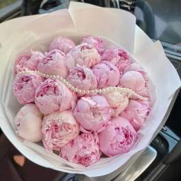 Pink peony bouquet wrapped in white paper with a pearl strand