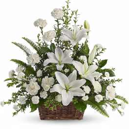 White lilies and carnations arranged in a wicker basket