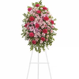 Standing floral spray with pink and red blooms on a white easel
