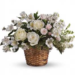 White roses and small white flowers arranged in a woven basket