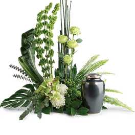 Green floral arrangement with orchids and tall stems in a black urn