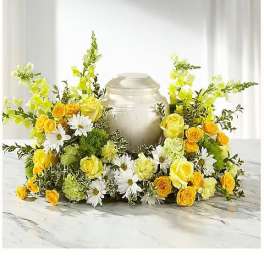 Yellow roses and white daisies arranged around a silver urn