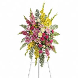 Tall standing floral spray with pink, yellow, and white flowers on a metal easel