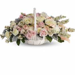 Low floral centerpiece with pink and cream roses in a white basket