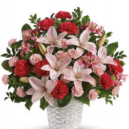 Pink lilies and carnations arranged in a white woven vase