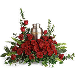 Red roses arranged around a silver urn with greenery