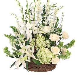 White floral arrangement in a wicker basket with lilies and roses