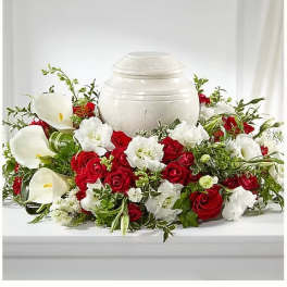 Red roses and white calla lilies arranged around a white urn