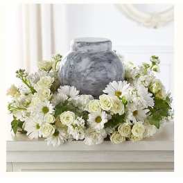 White daisies and cream roses arranged around a gray urn