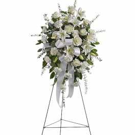 White floral standing spray with roses and lilies on an easel