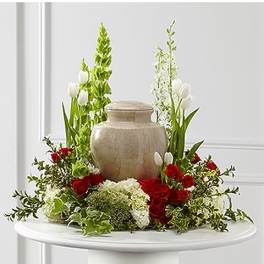 Red roses and white tulips arranged around a beige urn