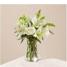 White lilies and roses arranged in a clear glass vase