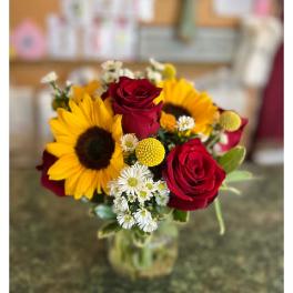 Bouquet of red roses and sunflowers in a glass vase