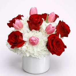 Red roses and pink tulips in a white vase with white hydrangeas