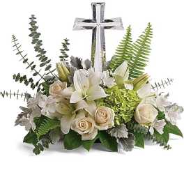 White lilies and cream roses arranged around a silver cross