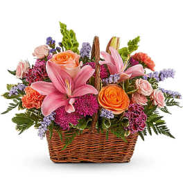 Mixed pink and orange flowers arranged in a wicker basket