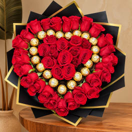 Heart-shaped bouquet of red roses with gold-wrapped chocolates