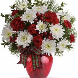 Red and white flower arrangement with plaid bow in a red glass vase