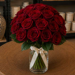 Bouquet of red roses in a clear glass vase with a cream ribbon
