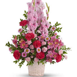Pink gladiolus and mixed pink flowers in a white woven basket