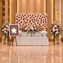 Funeral casket with red and white floral sprays in a chapel