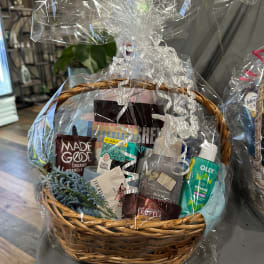 Gift basket with snacks, skincare items, and a small blue floral sprig